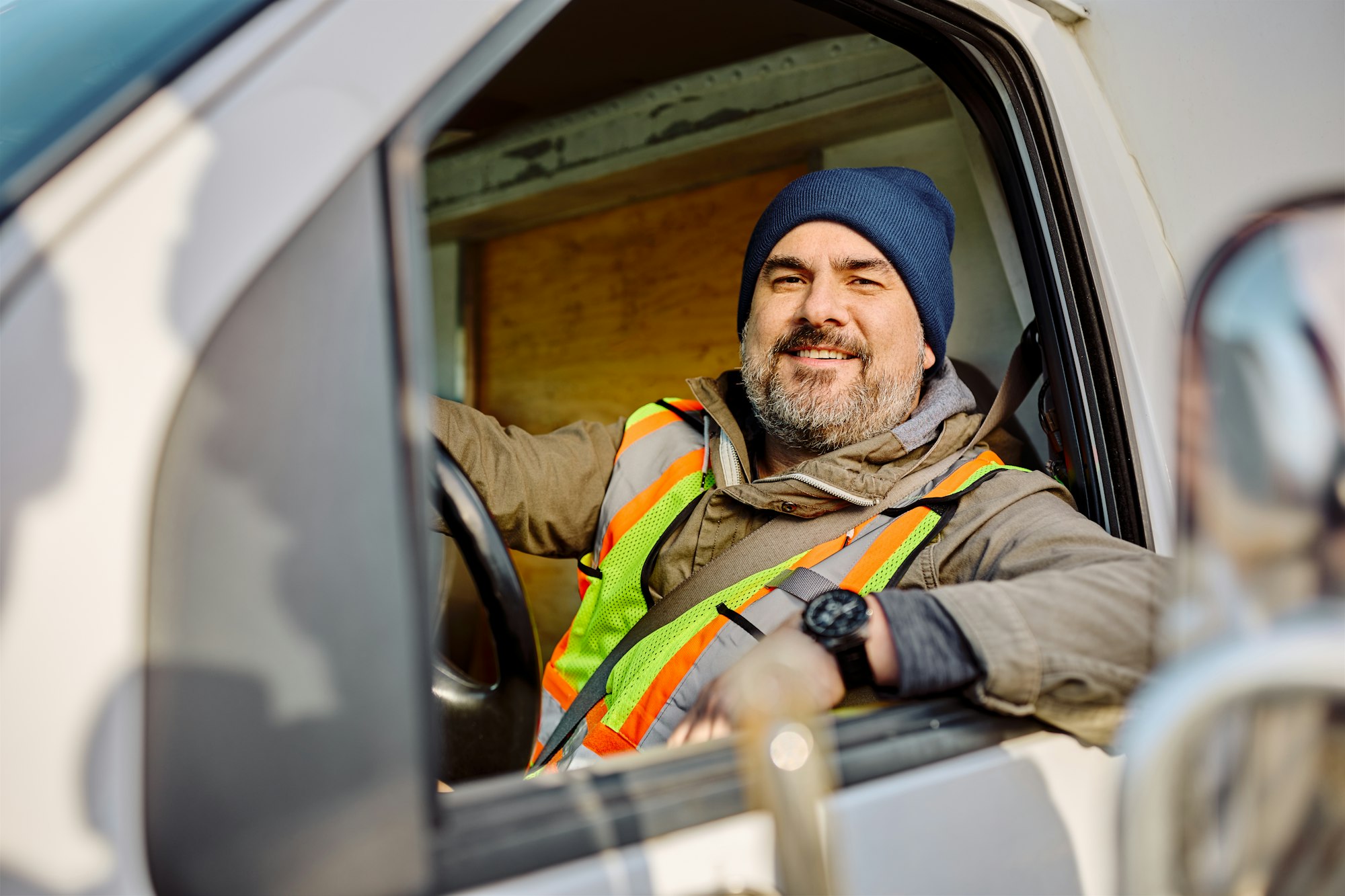 Happy truck driver sitting in vehicle cabin and looking at camera.